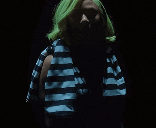 a woman with green hair is wearing a black and blue striped shirt