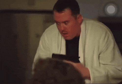 a man in a white sweater is holding a gun