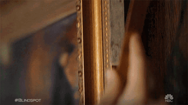 a close up of a person 's hand holding a picture frame with the nbc logo in the background