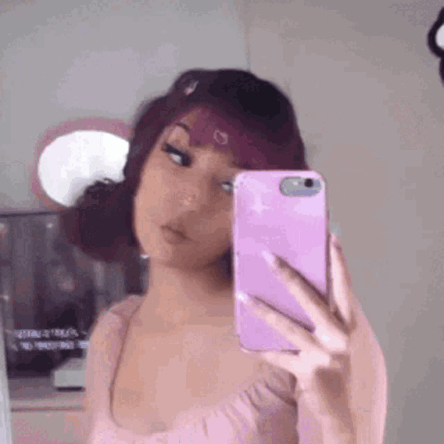 a girl is taking a selfie in front of a mirror with her cell phone .
