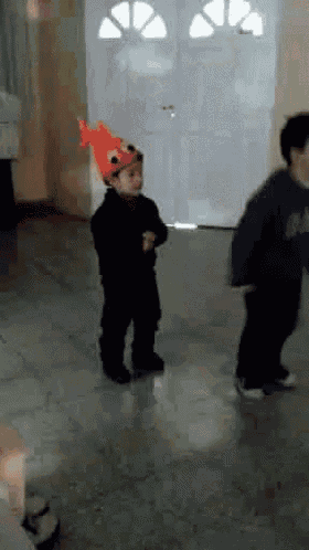 a young boy wearing a fish hat is dancing in a hallway