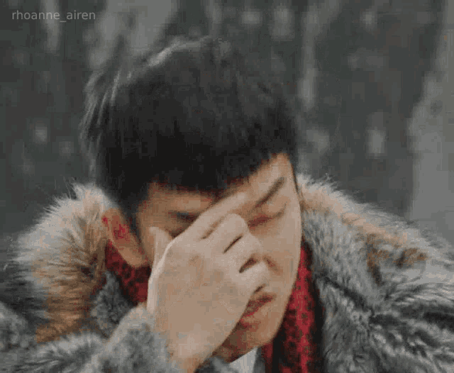a man in a fur coat is pointing his finger at his nose .