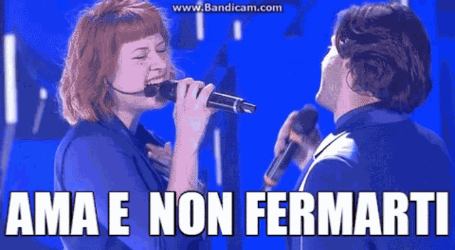 a woman singing into a microphone next to a man with the words ama e non fermarti above them