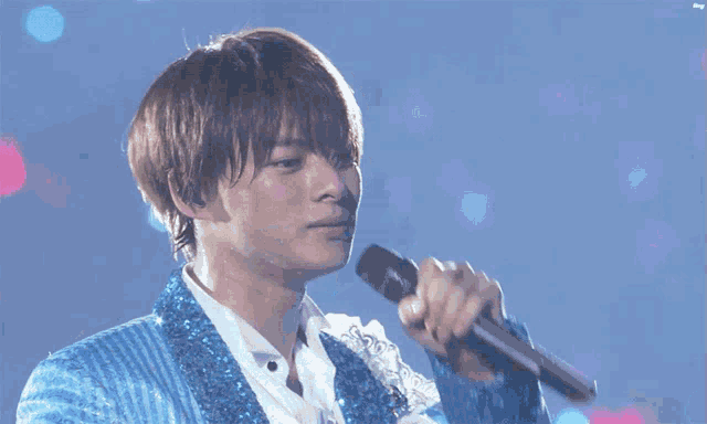 a man in a blue sequined jacket is reaching out towards the camera