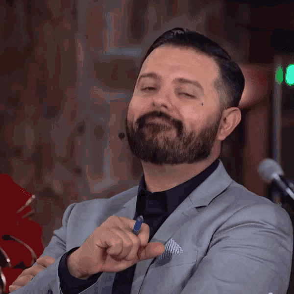 a man with a beard is wearing a suit and holding a blue pen