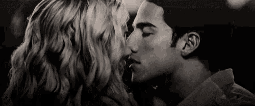a black and white photo of a man and woman kissing each other .