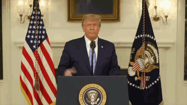 donald trump stands behind a podium that says president of the united states on it