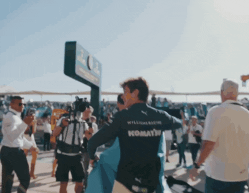 a man in a williams racing komatsu shirt stands in a crowd
