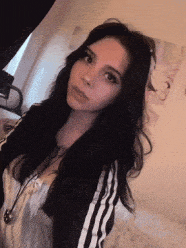 a woman with long black hair is wearing a black and white striped jacket
