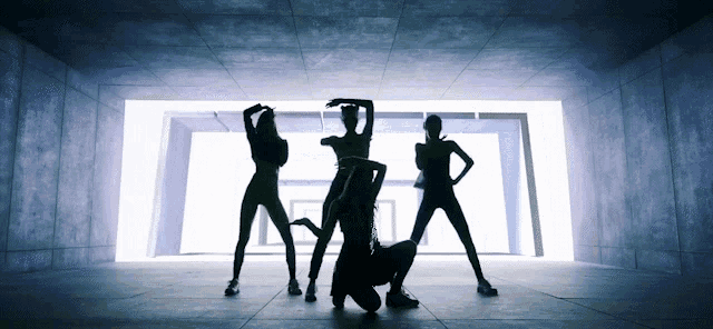 a group of female dancers are silhouetted in a dark room