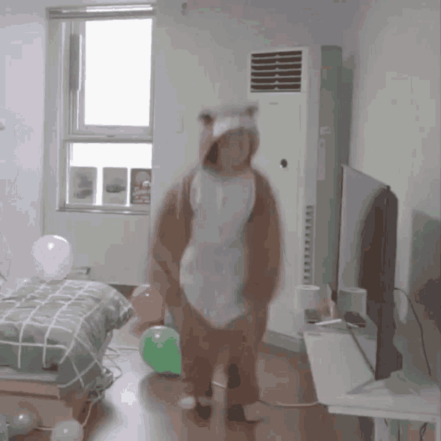 a person in a bear costume is dancing in a room with balloons and a tv