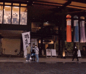 a group of people standing in front of a building with a banner that says ' tokyo '