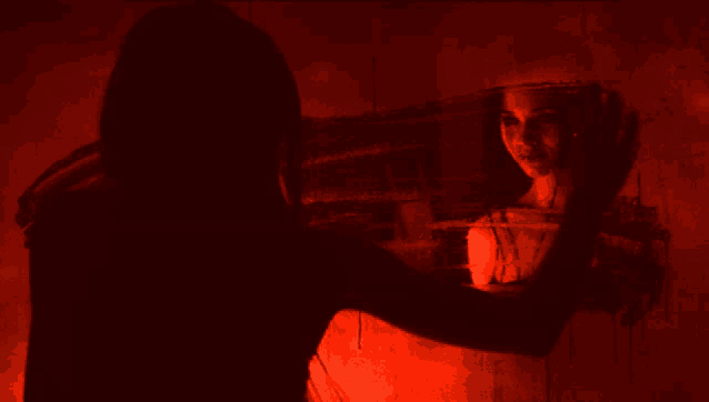 a woman looks at her reflection in a mirror