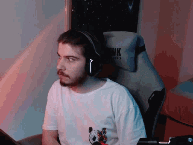 a man wearing headphones sits in a chair that says wk
