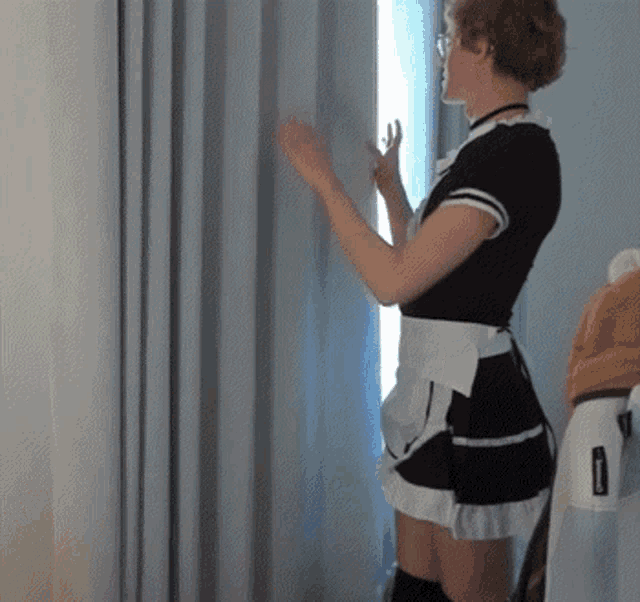 a woman in a maid costume is looking out a window