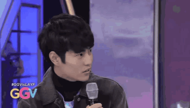 a man is holding a microphone in front of a ggv sign