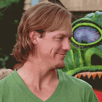 a man in a green shirt is smiling in front of a monster