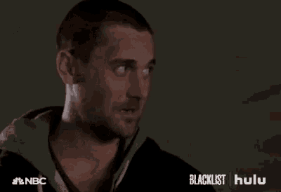 a man in a black hoodie is smiling with his eyes closed and his mouth open .