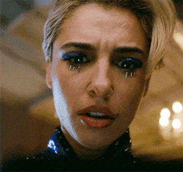 a close up of a woman 's face with blue eye shadow and spikes on her eyelashes