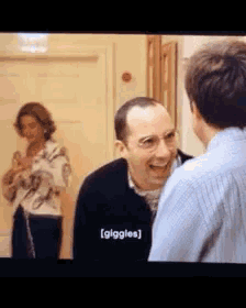 two men are laughing in front of a woman and the word giggles is displayed on the screen