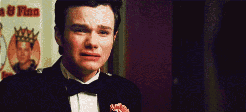 a man in a tuxedo is crying in front of a sign that says ' finn ' on it