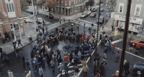 a crowd of people are gathered at an intersection in front of a fisher pharmacy