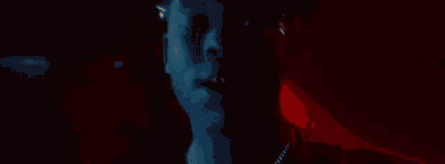 a man is singing into a microphone in a dark room in front of a red light .