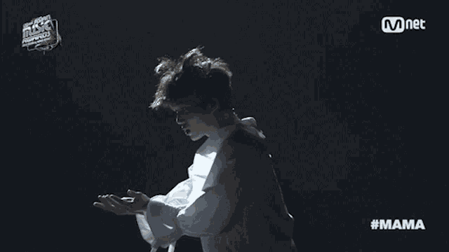 a man in a white shirt is dancing in front of a mnet banner