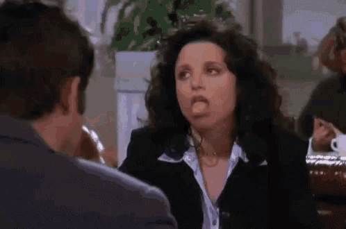 a woman is sticking out her tongue while talking to a man .