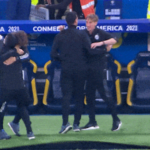 a group of people are hugging on a field with a sign that says conmebol america 2021