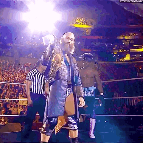 a man with a beard is standing in a wrestling ring holding a championship .
