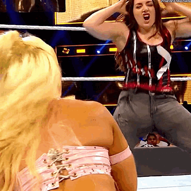 a woman in a wrestling ring screams at another woman in a pink top