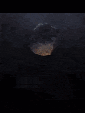 a large rock is surrounded by flames and smoke in a dark room .