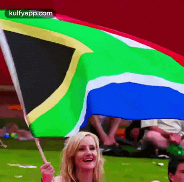 a woman is holding a south african flag and smiling at the camera
