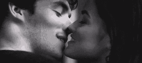 it is a black and white photo of a man and woman kissing .