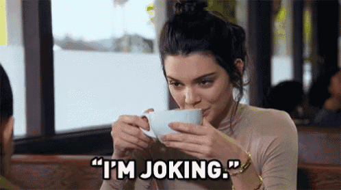 a woman is drinking a cup of coffee in a restaurant and saying i 'm joking .