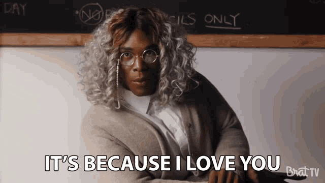 a woman says it 's because i love you in front of a blackboard with pencils only written on it