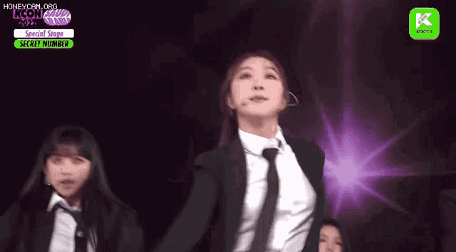 a woman in a suit and tie is performing on stage .