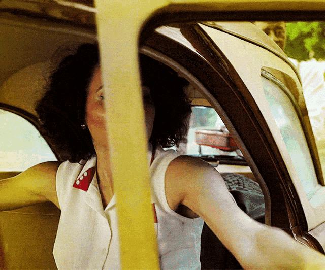 a woman sitting in a car with her arm out the window