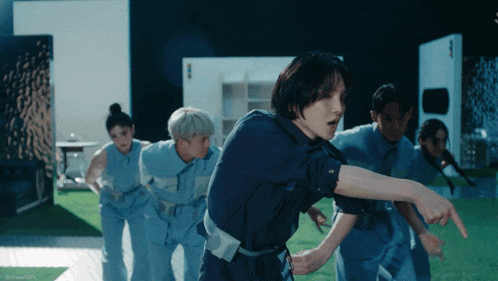 a group of people are dancing and one of them is pointing at the camera