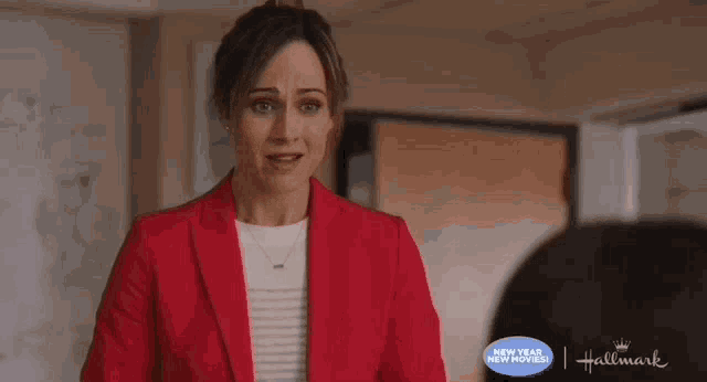 a woman in a red jacket is standing in a room talking to another woman .