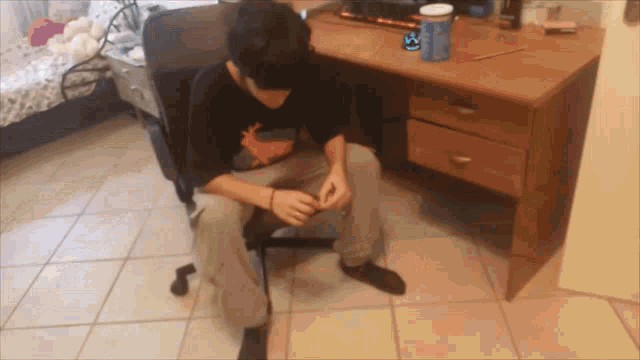 a man in a black shirt with a deer on it sits in a chair