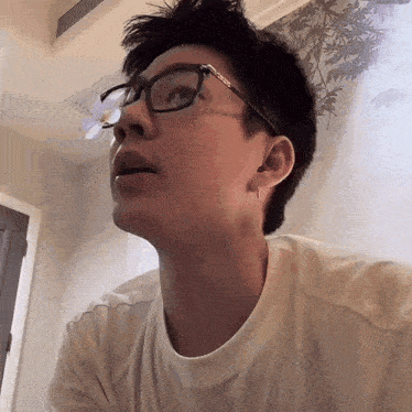 a young man wearing glasses and a white shirt looks up