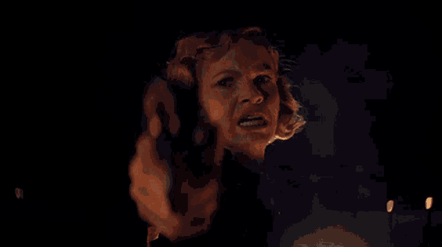 a woman screams in the dark with her mouth open