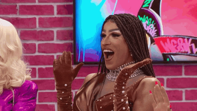 a drag queen is laughing in front of a screen that says weekly