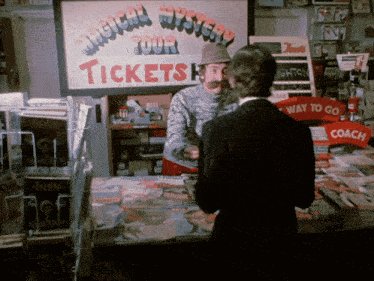 a man standing in front of a sign that says tickets