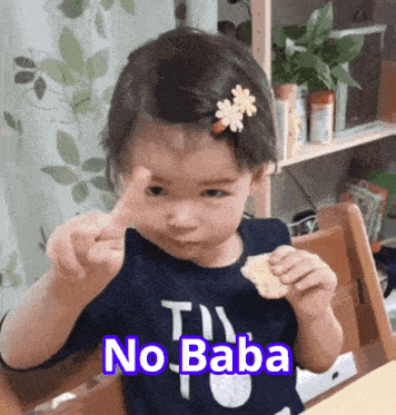 a little girl with a flower in her hair is sitting at a table with the words no baba written on the bottom