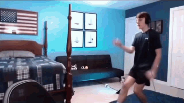a young man is dancing in a bedroom in front of a bed .
