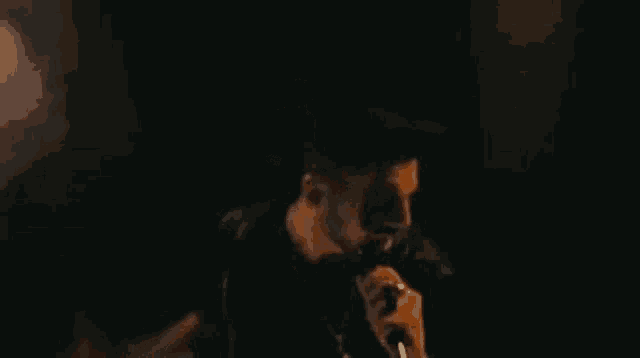 a man is smoking a cigarette in a dark room in a dark room .
