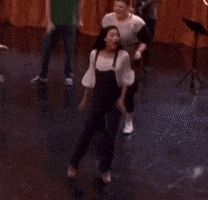 a group of people are dancing on a stage with a man playing a trumpet